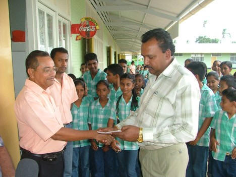 Bharat Jairam (rechts), voorzitter van de VVN, overhandigt een cheque aan schoolleider Tjon A San van de openbare school Laigsingh, in de Corantijnpolder. Met het geld zal een fietsenstalling gebouwd worden.